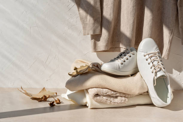 Pile of eco-friendly clothing and shoes in neutral tones, representing sustainable fashion trends.